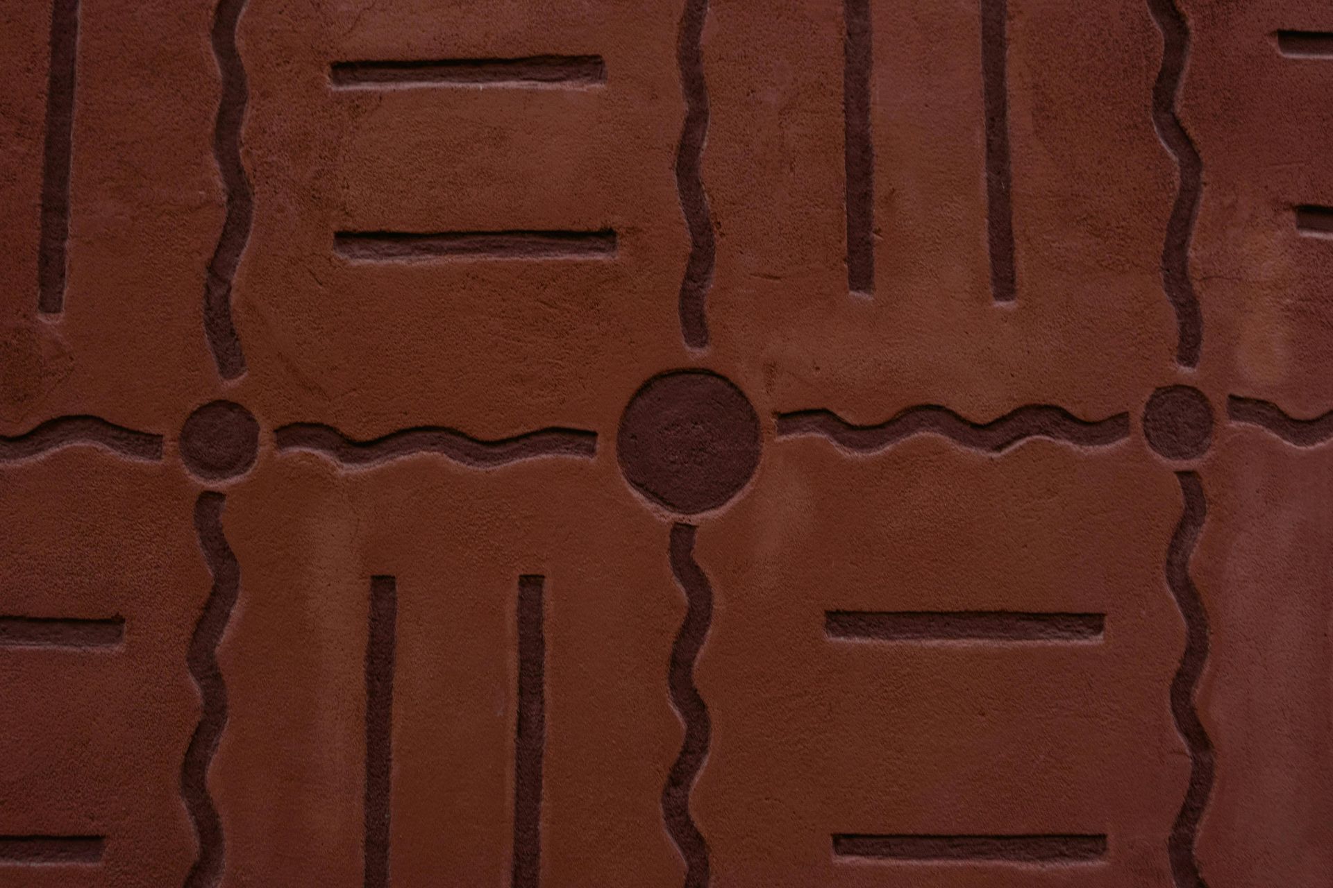 Close-up of a reddish-brown tiled surface with geometric grooves and circular accents