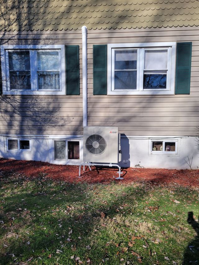 House exterior with two windows, green shutters, and a small air conditioning unit below.
