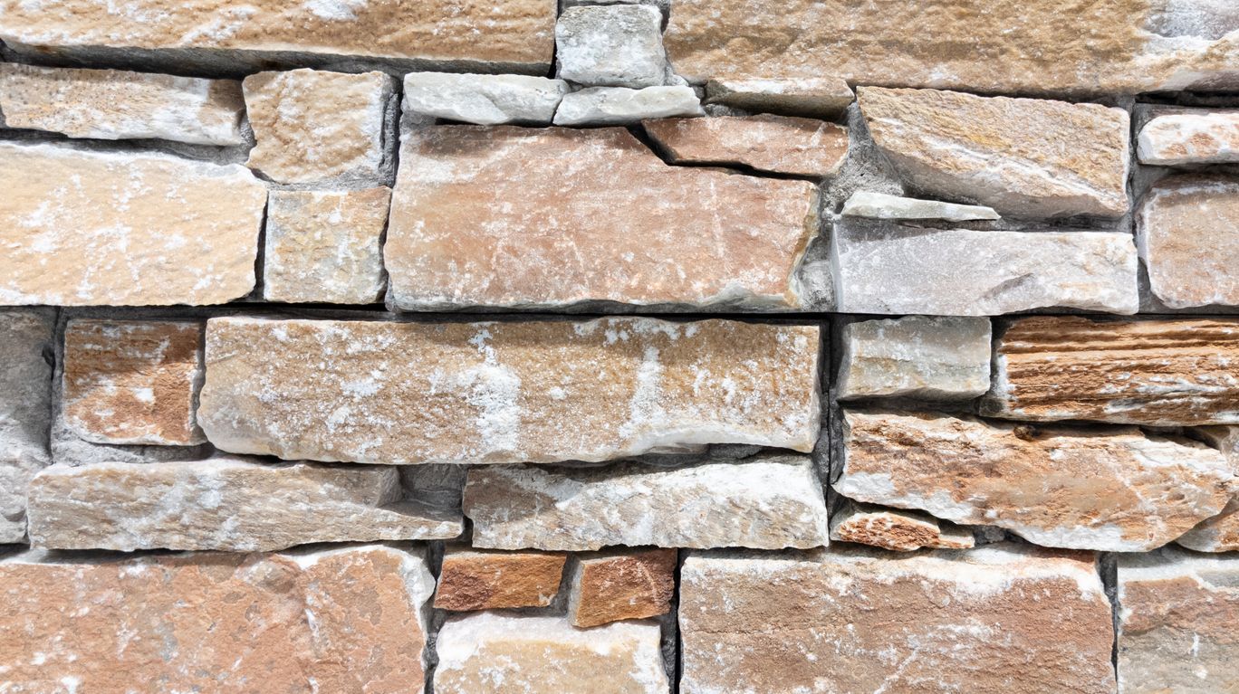 Un primer plano de un muro de piedra hecho de diferentes tipos de rocas.