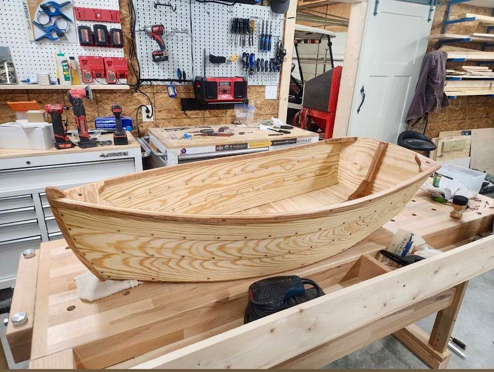 A wooden boat is sitting on top of a wooden table in a workshop.