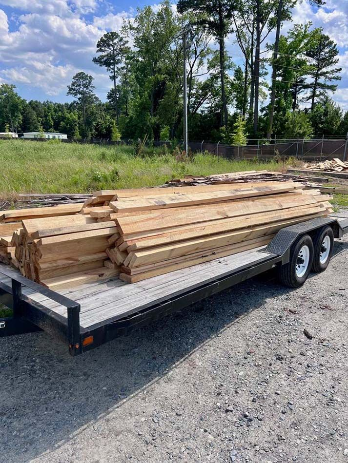 A trailer filled with wooden boards is parked on the side of the road.