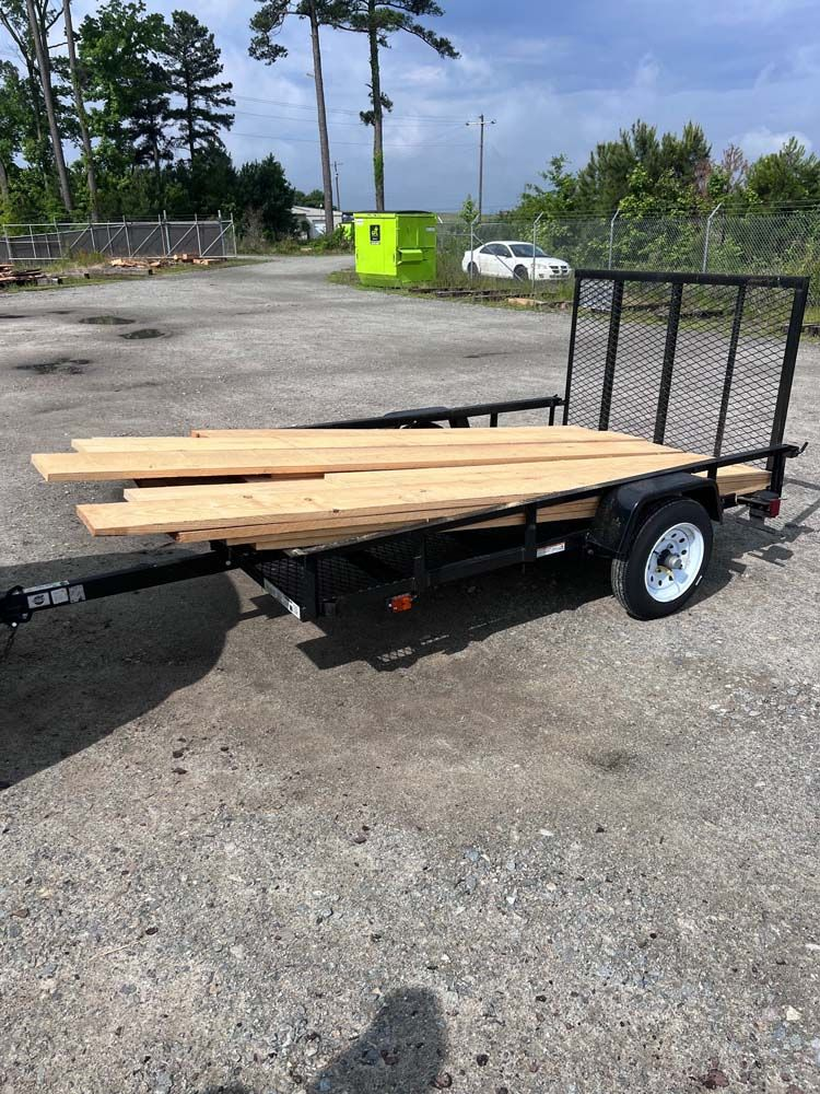 A trailer with a bunch of wood on it is parked in a parking lot.