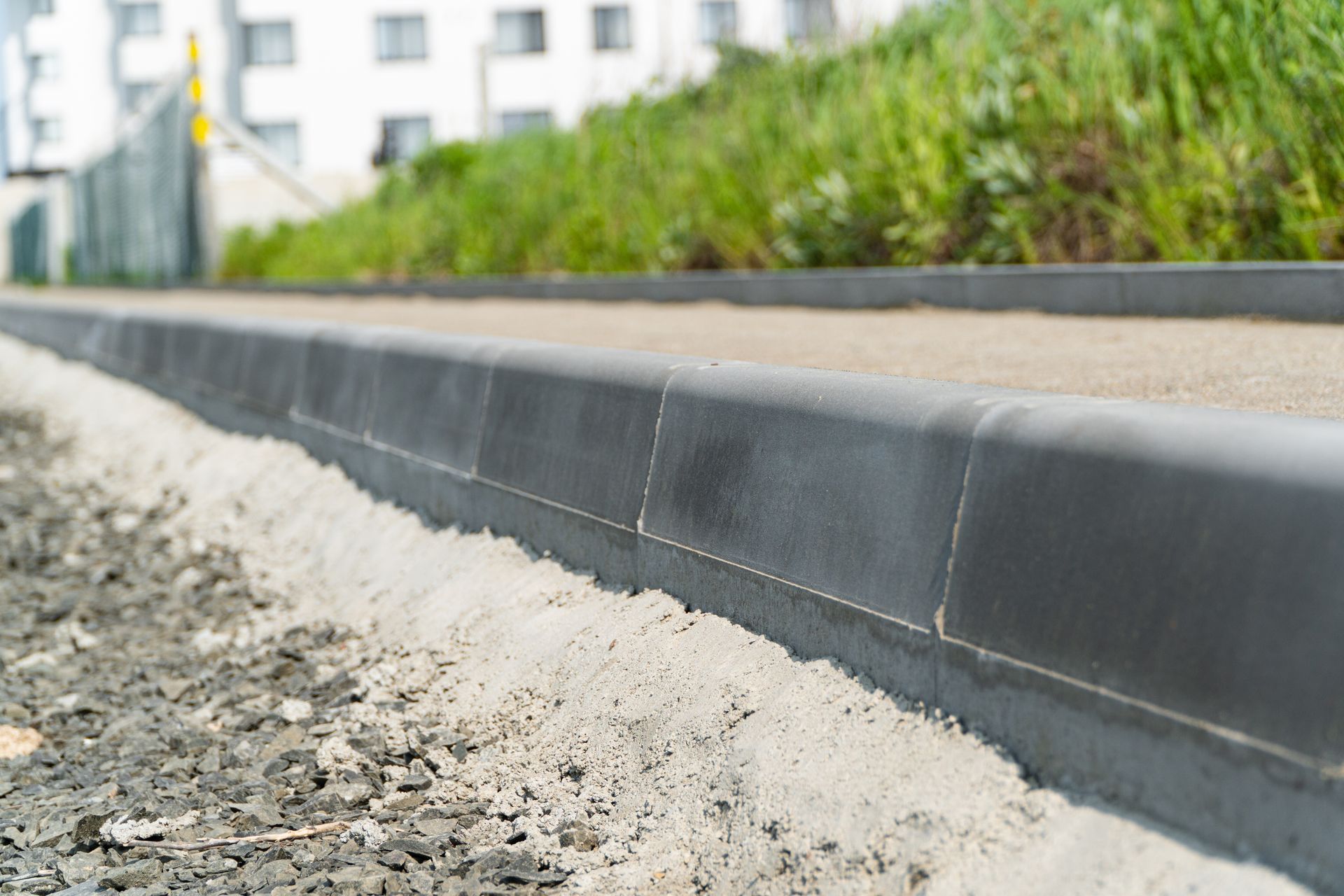 A concrete curb is being installed on the side of a road.