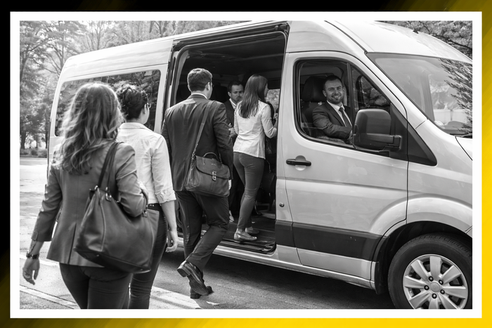 People boarding a white passenger van with the sliding door open on a roadside.