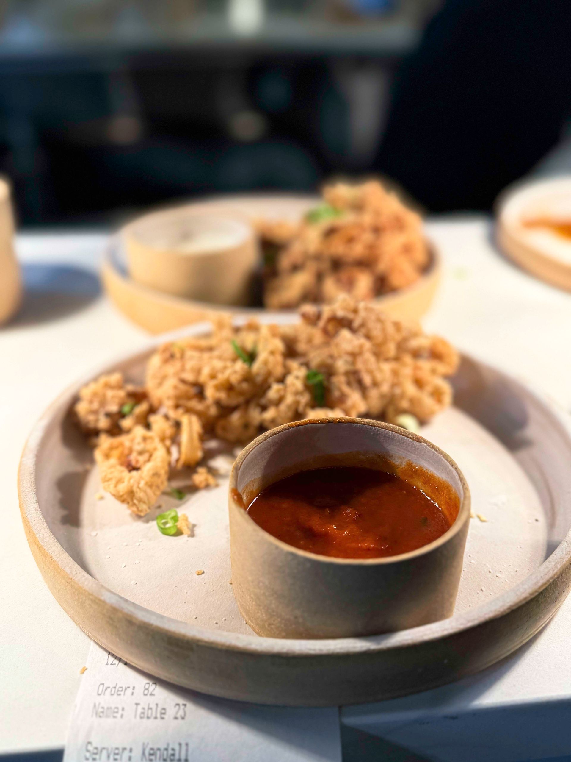 Fried chicken with dipping sauce on a beige plate.