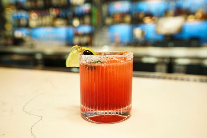 Cocktail with lime and chili rim on a bar counter.