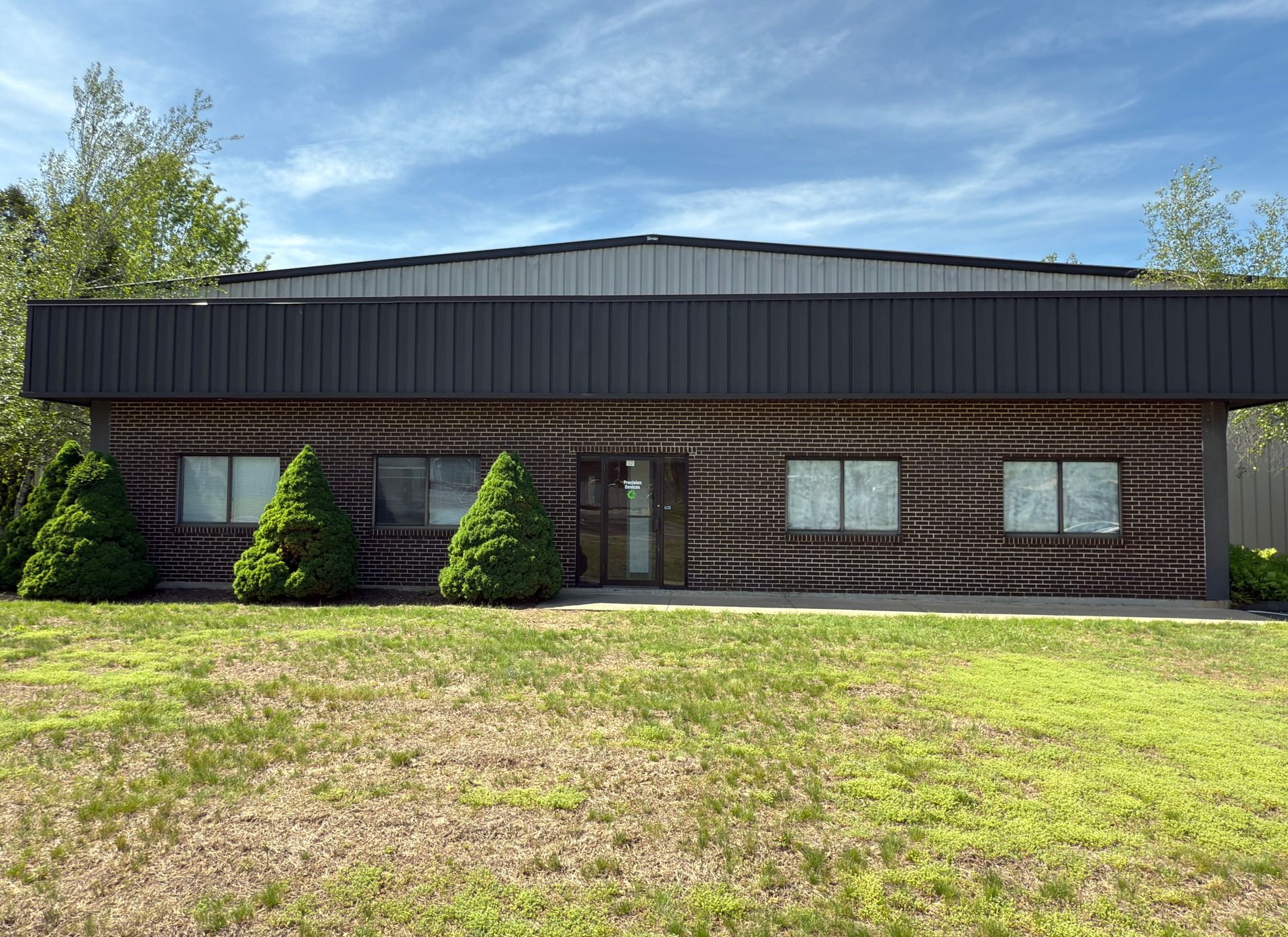 A brick building with a black roof and a lot of windows