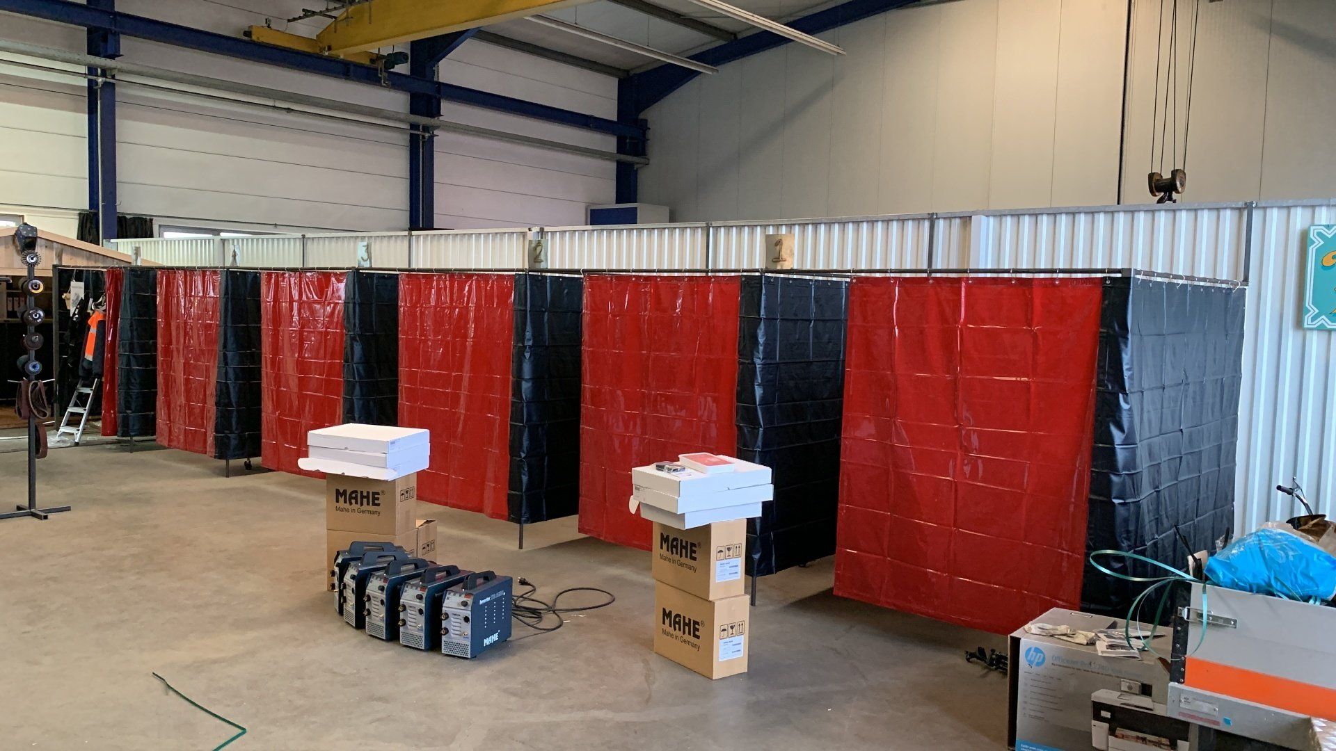 Laswerkplaatsen in een werkplaats; afwisselend rode en zwarte gordijnen scheiden ze.