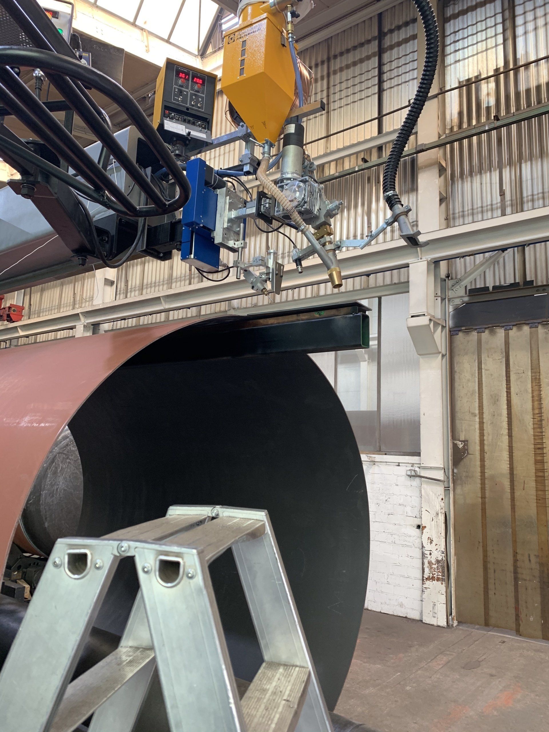 Een geautomatiseerde lasmachine snijdt een grote metalen plaat in een fabrieksomgeving.