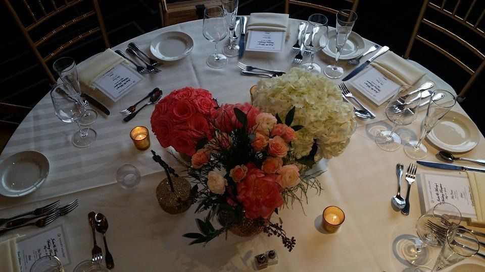 Round banquet table set with white linens, candles, and colorful floral centerpiece in the middle