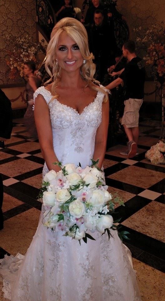 Woman in a white wedding dress holding a pastel bouquet at an indoor reception