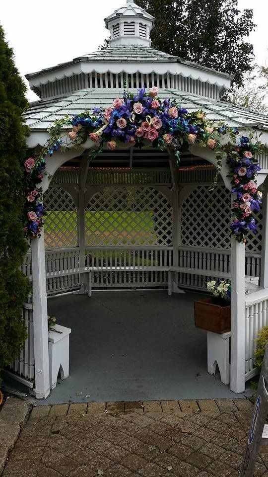 White gazebo with floral decorations and lattice walls in a garden setting