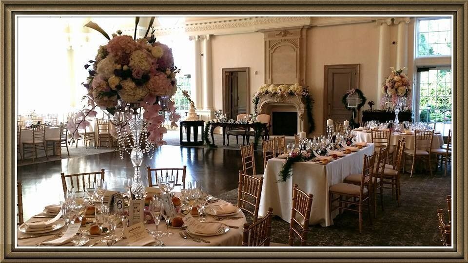 Elegant formal dining room with set tables, floral centerpieces, and gold-trimmed decor in a bright hall
