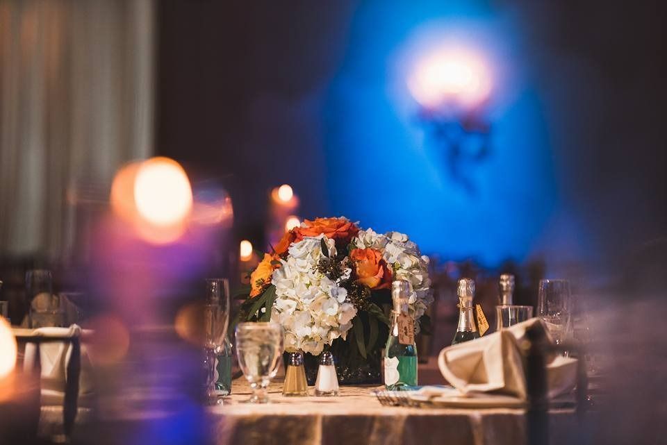 Elegant banquet table with white floral centerpiece and warm candlelight in a softly blurred venue