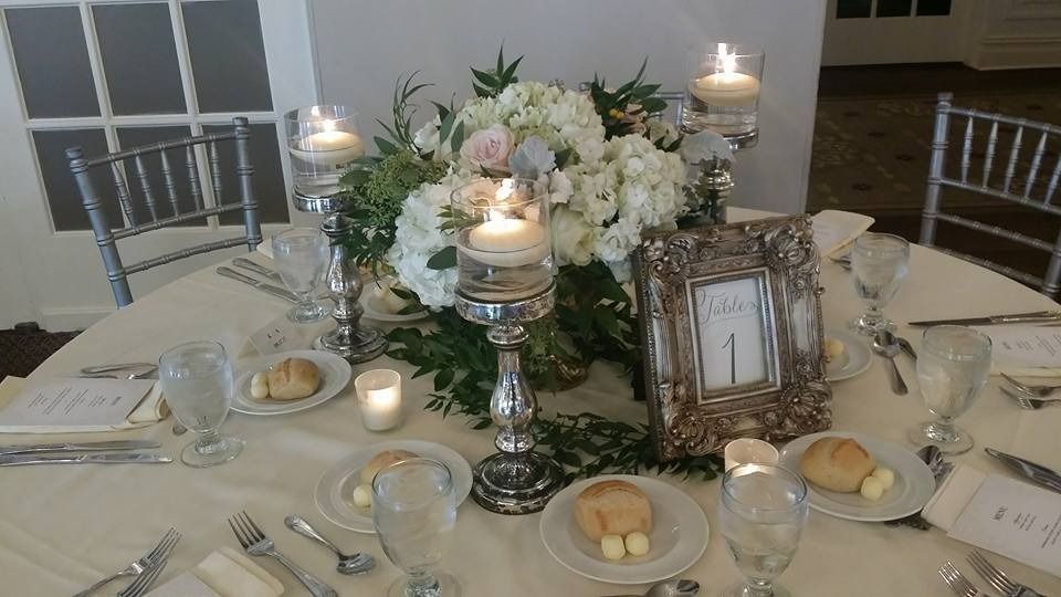 Elegant dinner table with white floral centerpiece, lit candles, glassware, and place settings