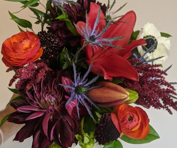 Mixed bouquet of red, orange, pink, and white flowers with green leaves