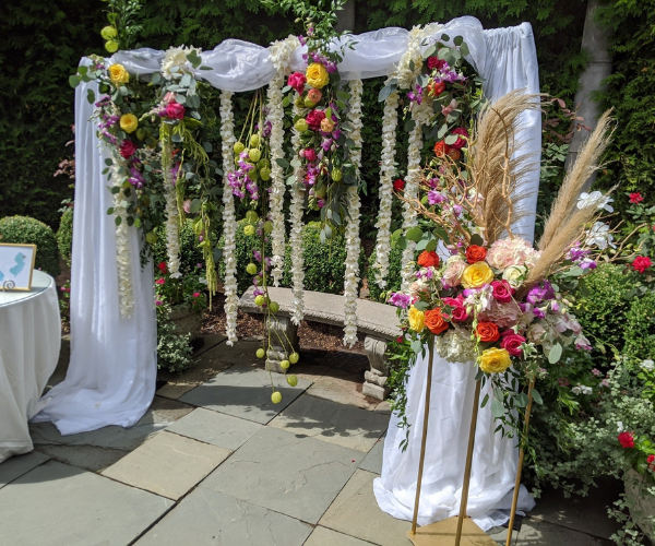 Flower-decorated wedding swing with white drapes and colorful garlands in a garden
