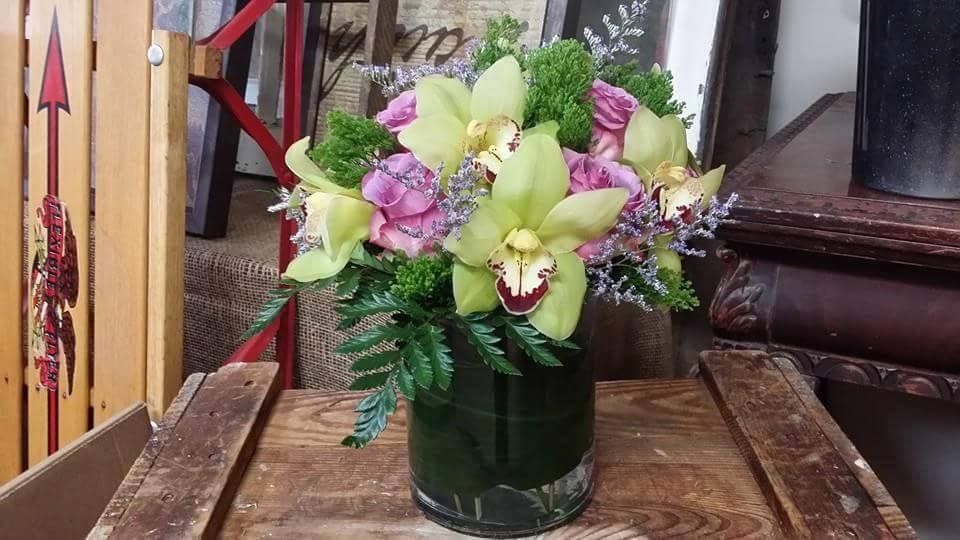 Bouquet of pink and white flowers in a glass vase on a wooden table indoors