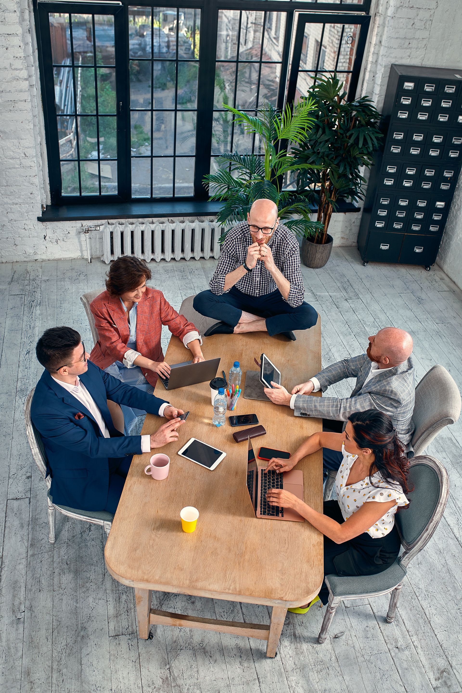 A group of people are sitting around a table with laptops.