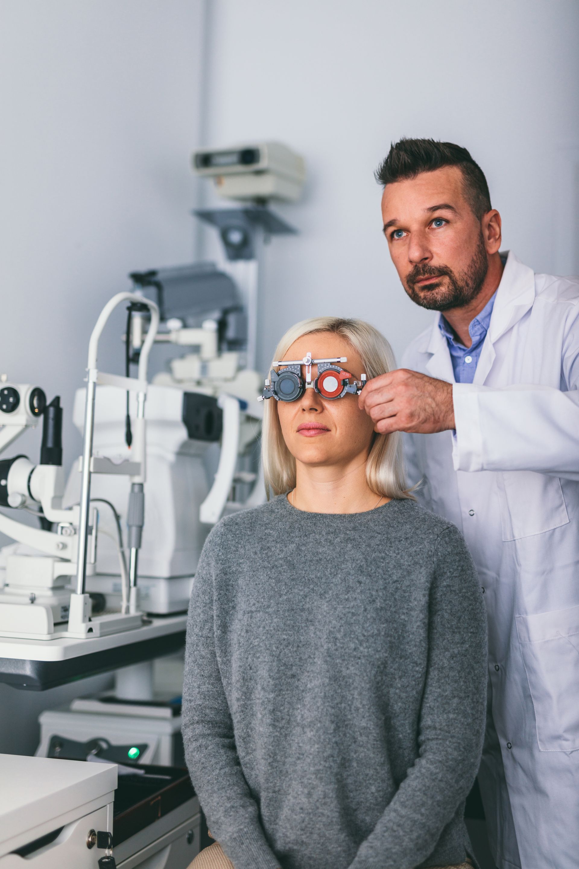 An ophthalmologist is examining a woman 's eye in an optical shop.