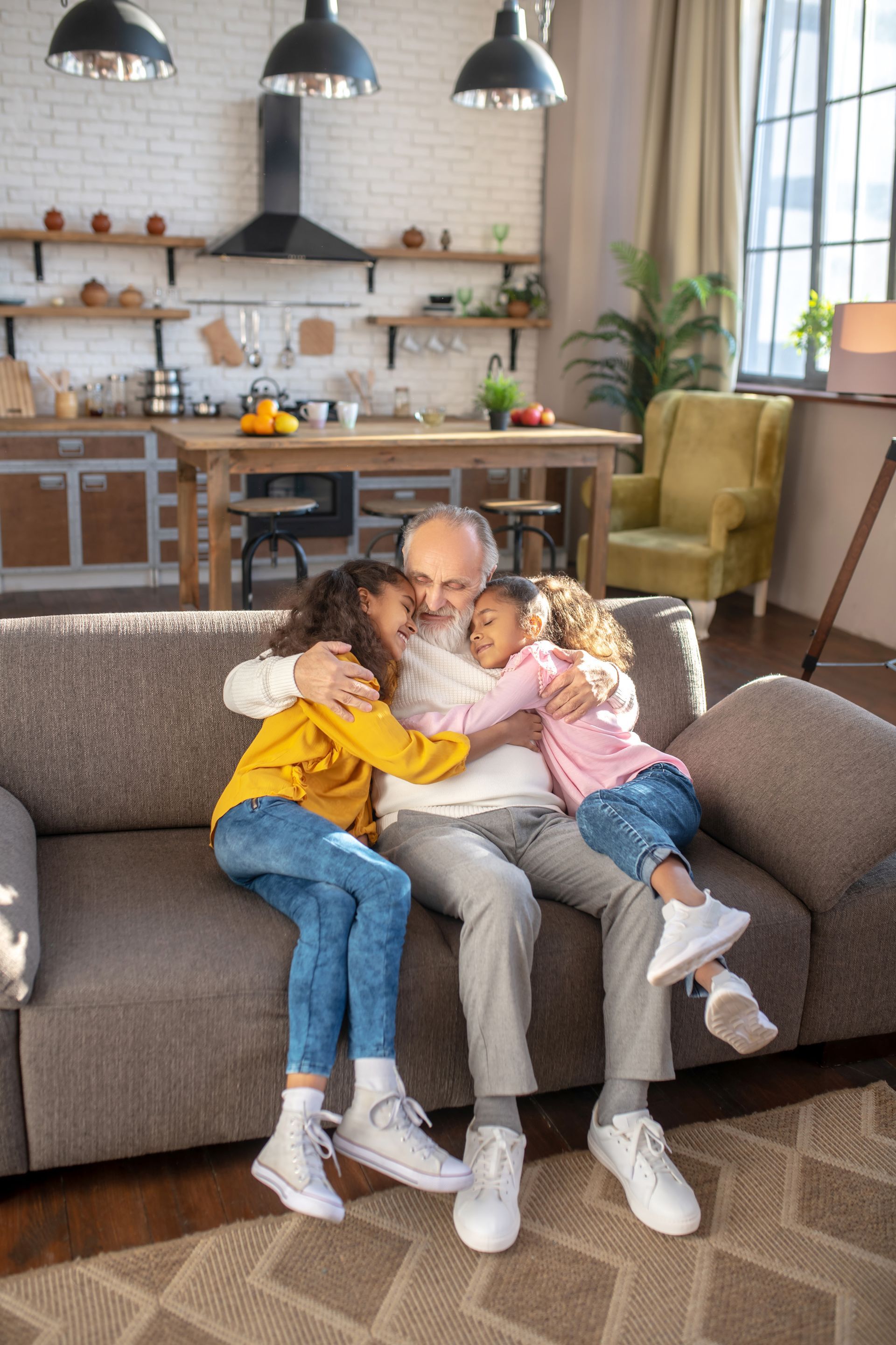 A man and two children are sitting on a couch hugging each other.