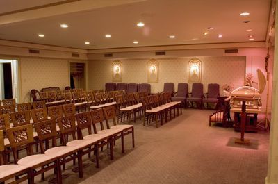 Interior of a funeral home with rows of chairs, a podium, and soft lighting.