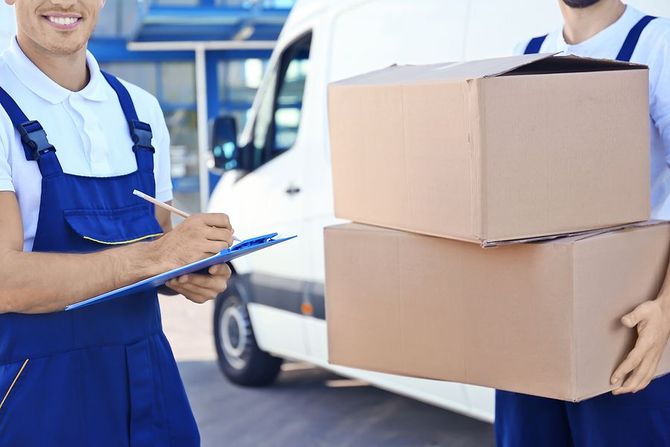 Movers with boxes and clipboard by delivery van.