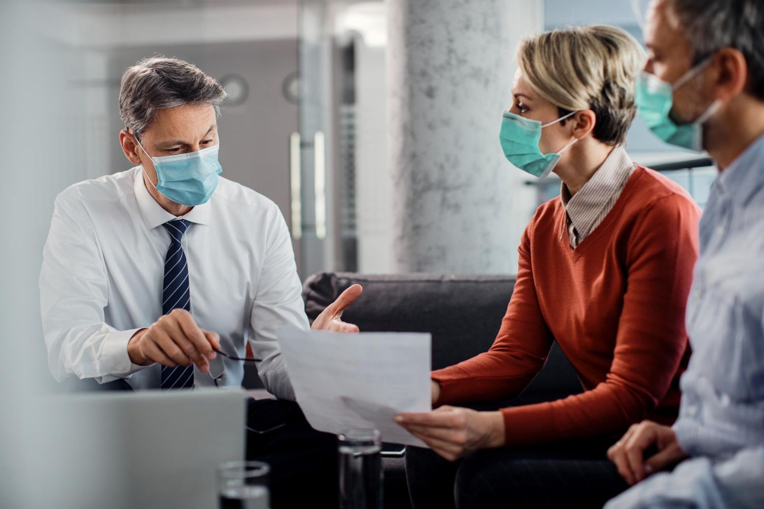 Three masked coworkers reviewing a document in an office meeting