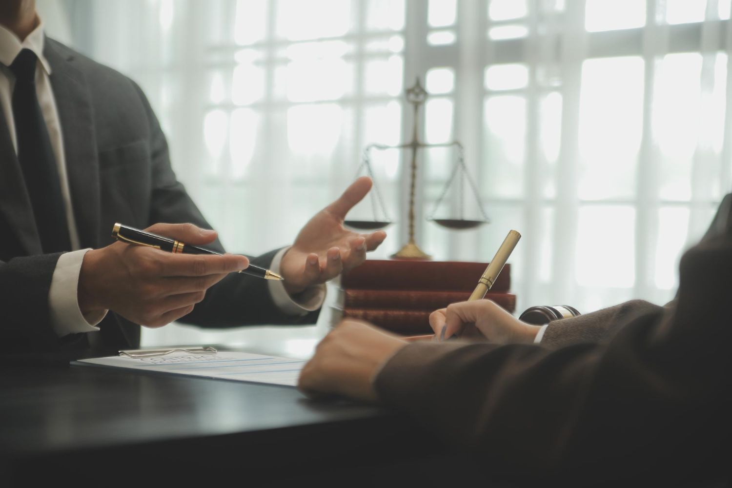 Two businesspeople discussing a contract at a table with a scale of justice in the background