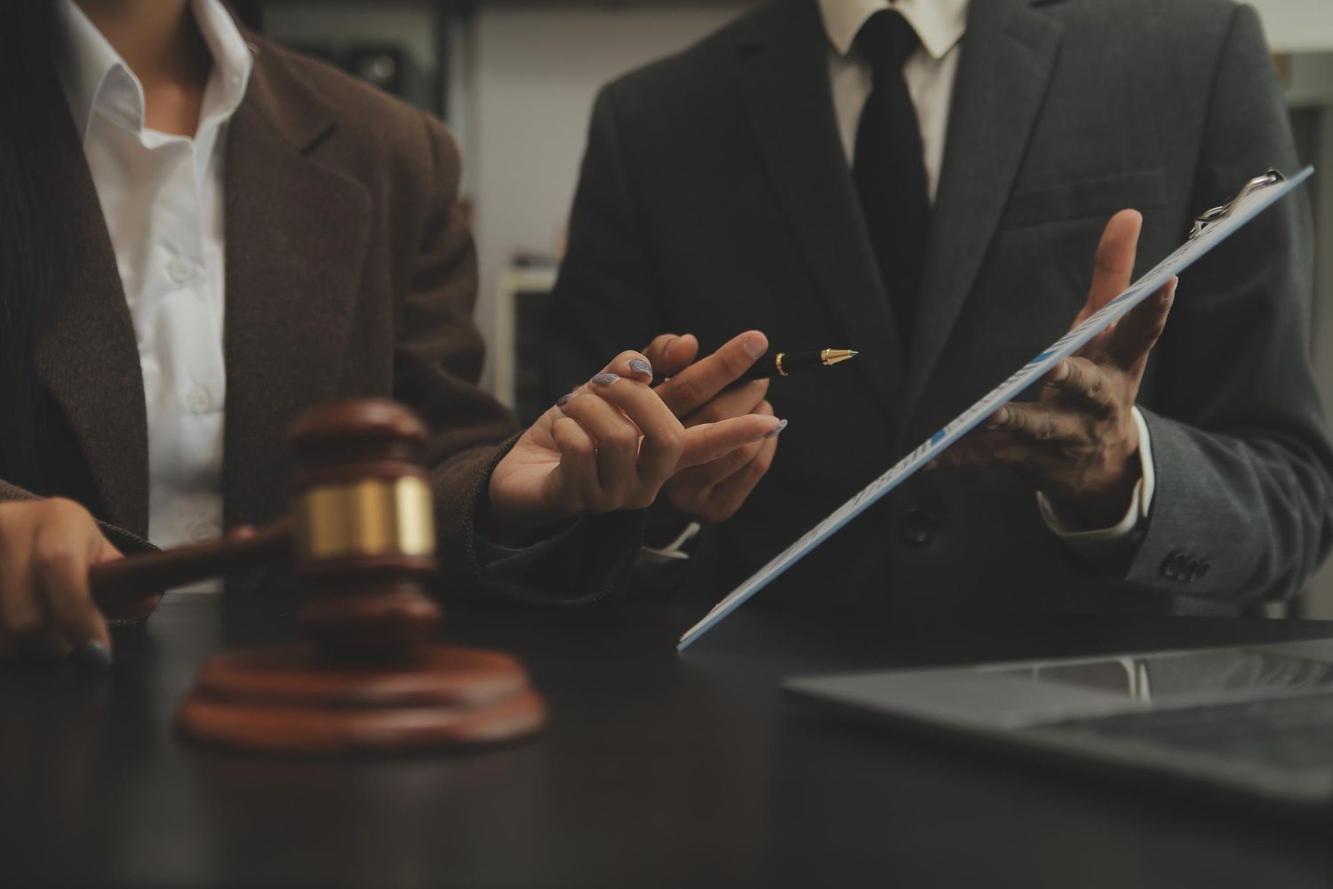 Lawyers in suits discussing a case with a gavel and clipboard on the table