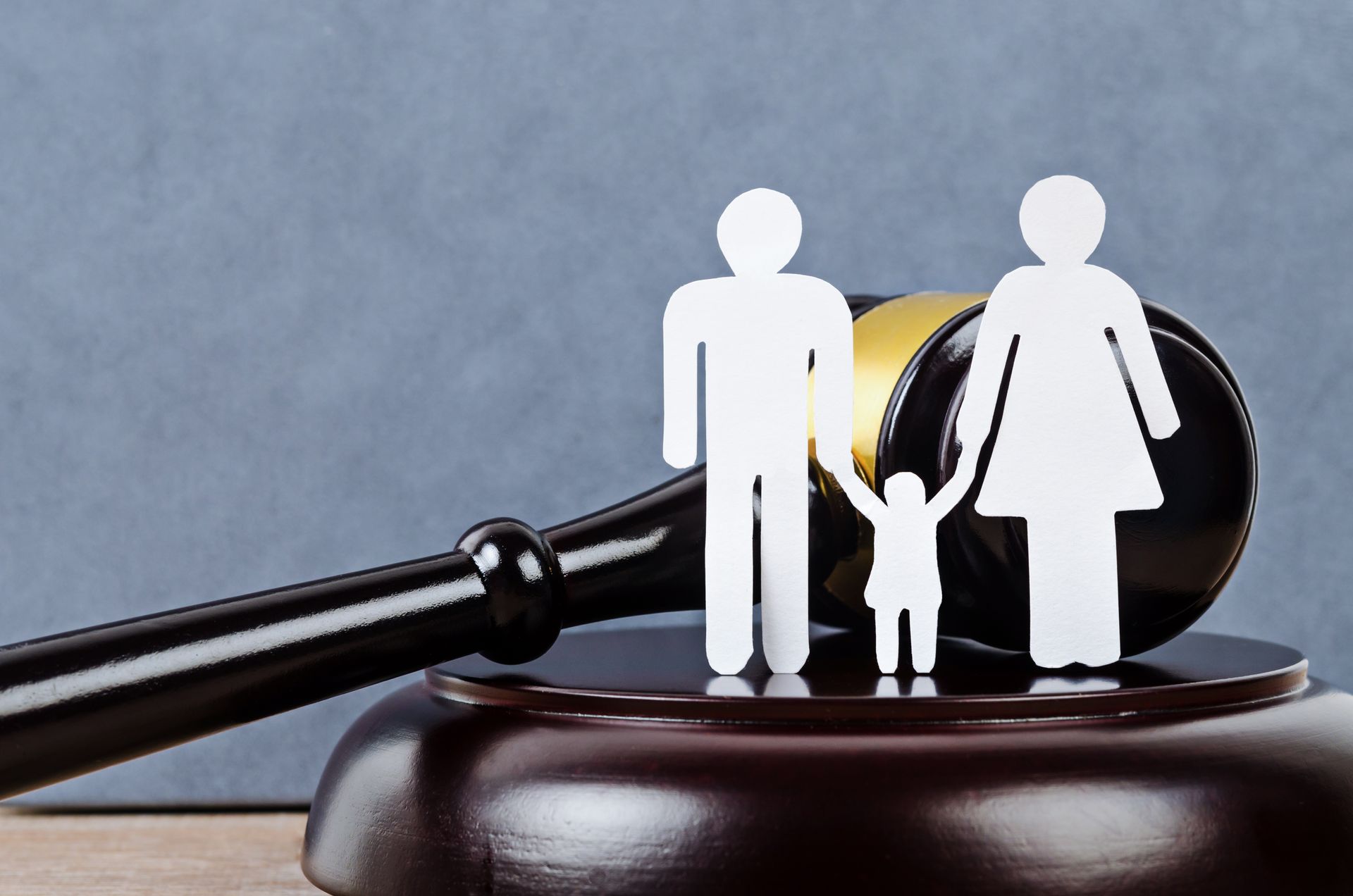 Paper cutout family with child standing beside a judge's gavel. Paper cutout family with child standing beside a judge's gavel.