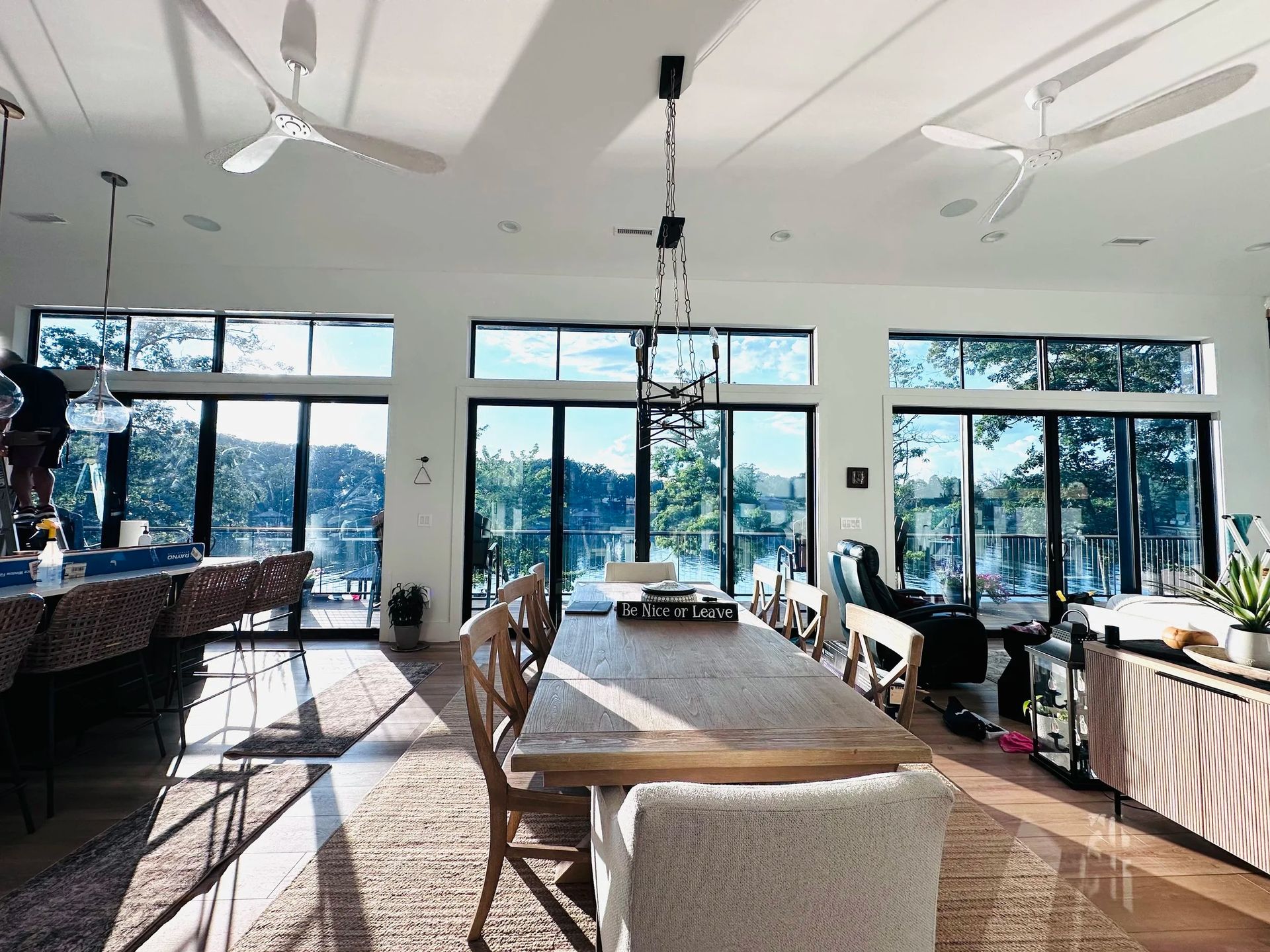 White house with porch, steps, and large black windows under a blue sky.