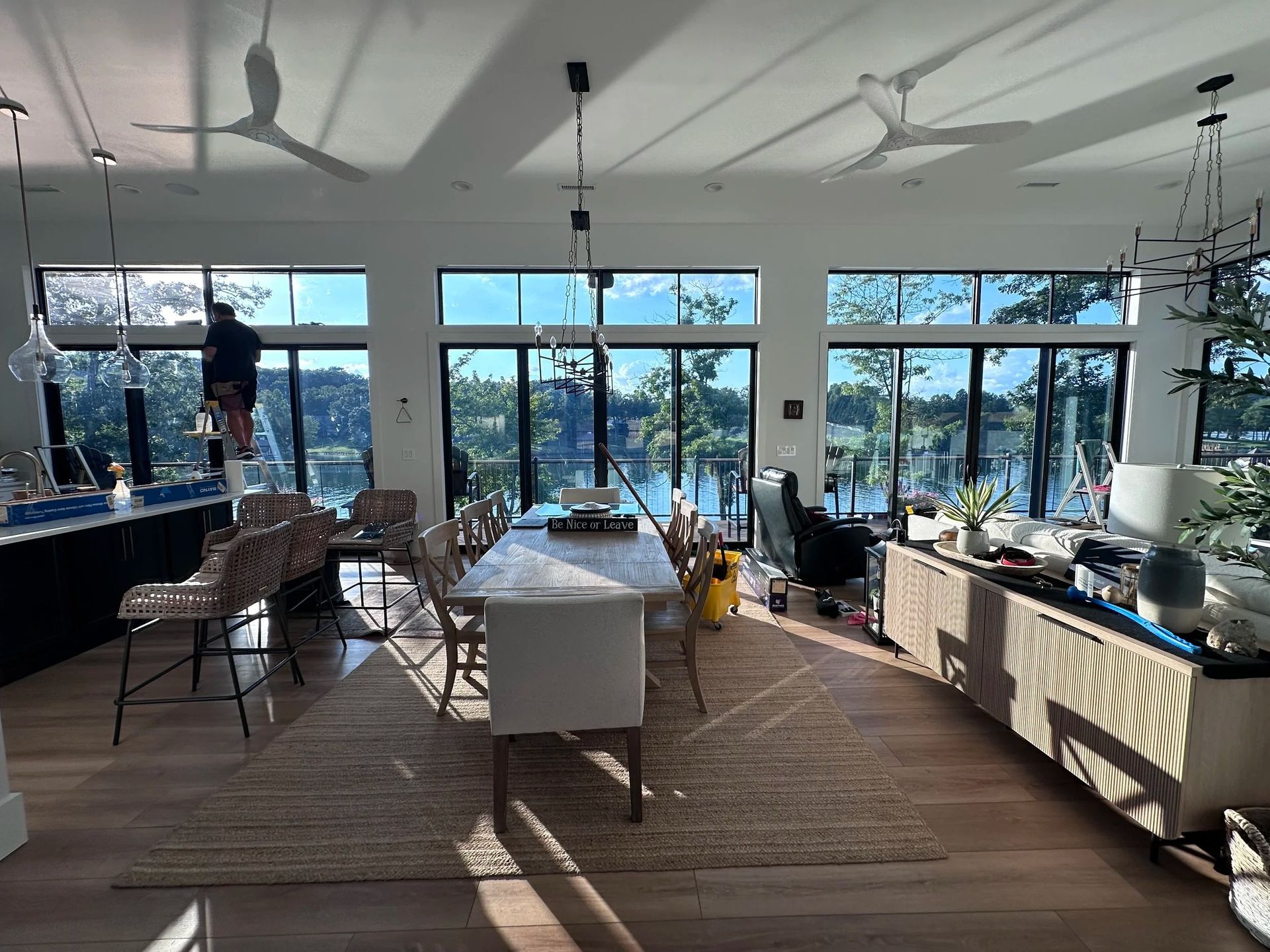 White house with porch, steps, and large black windows under a blue sky.