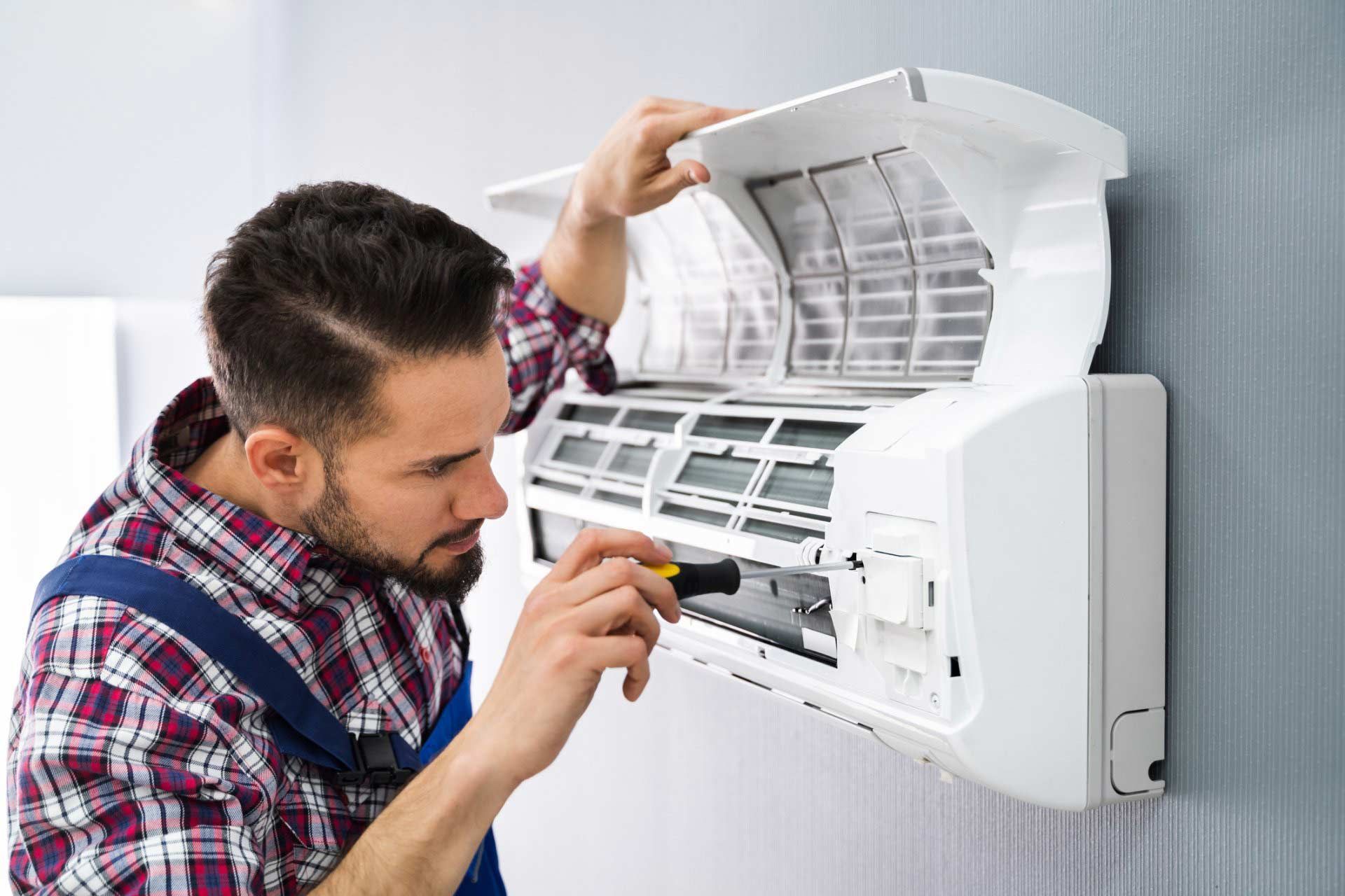 Technician cleaning a wall-mounted air conditioner with the front panel open