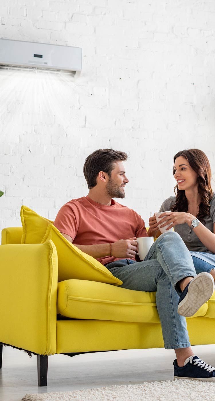 Two people talking on a bright yellow sofa in a white living room.