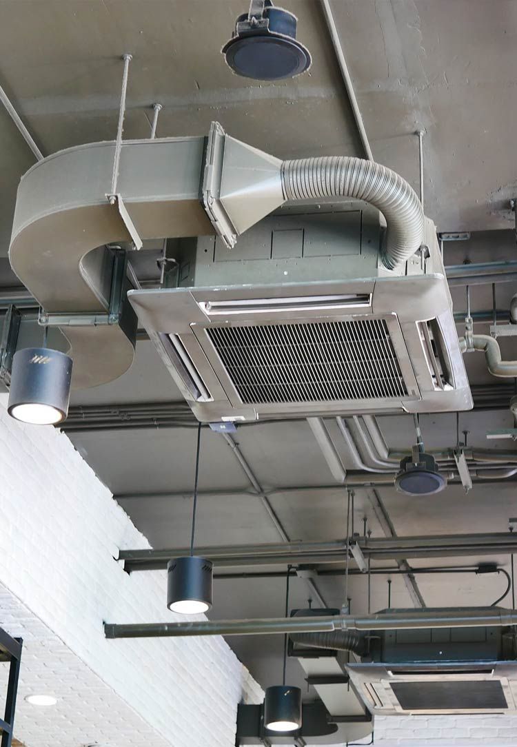 Ceiling with exposed ducts, vents, and hanging lights in an industrial interior