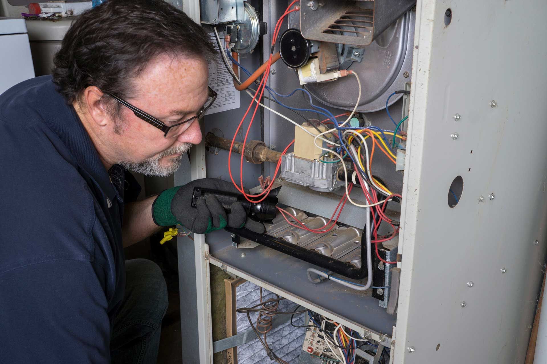 Technician inspecting wiring inside an open electrical cabinet.