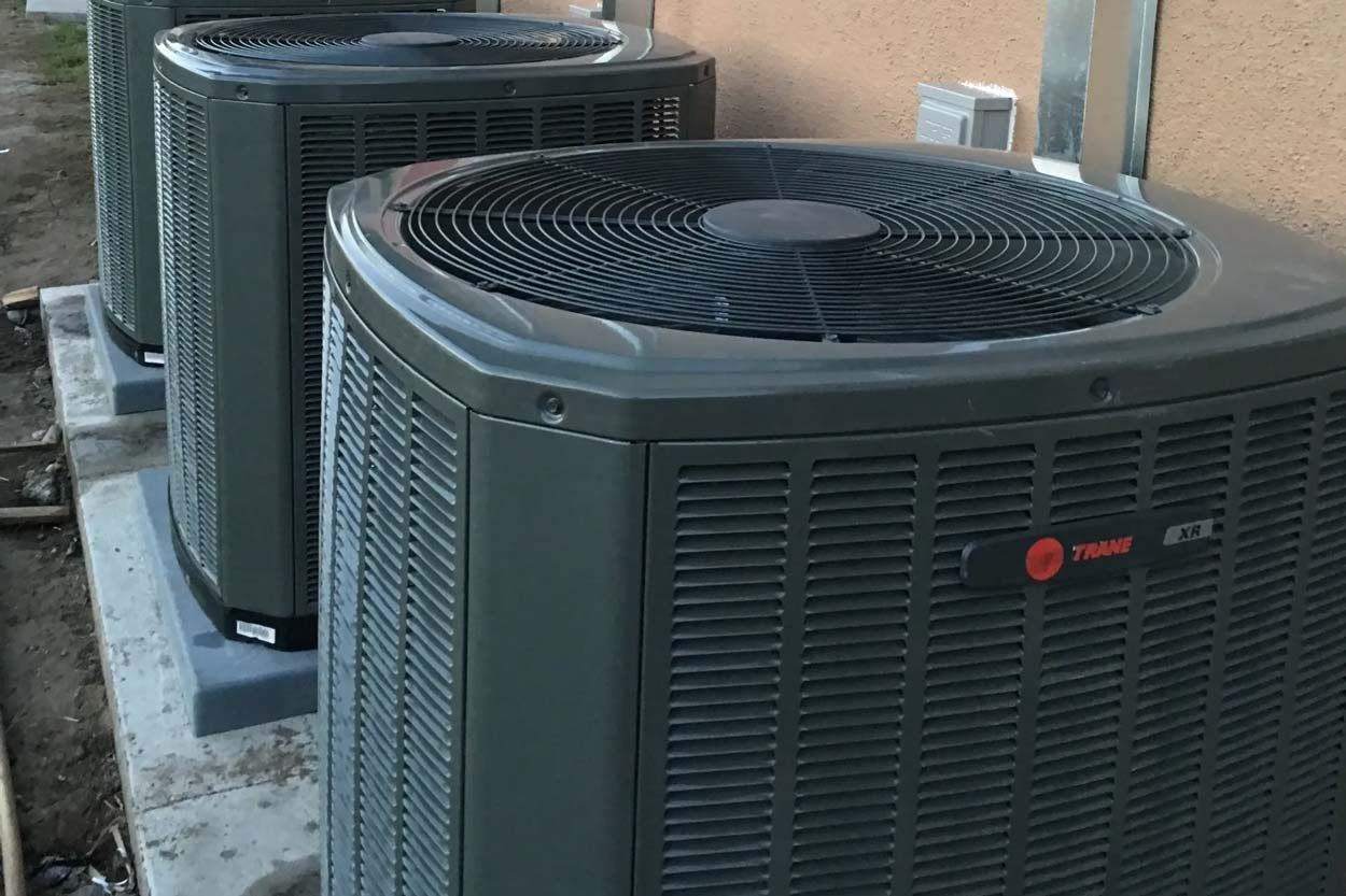 Two outdoor Trane air conditioning units beside a building wall