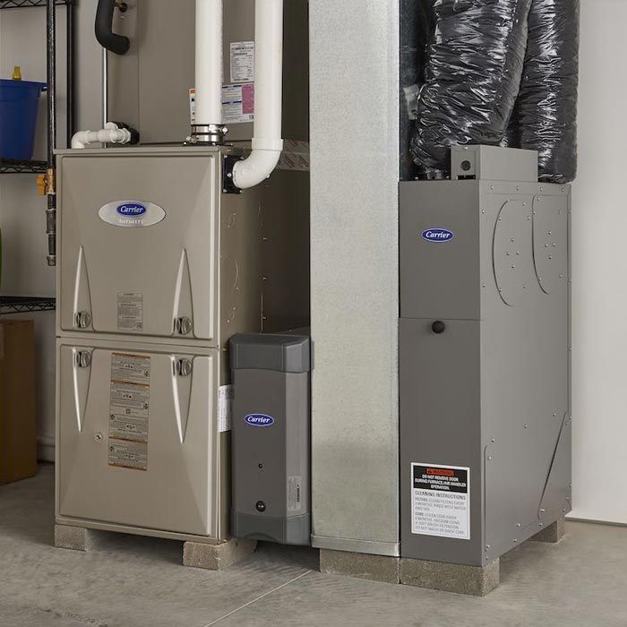 Two gray HVAC furnaces and ductwork in a utility room