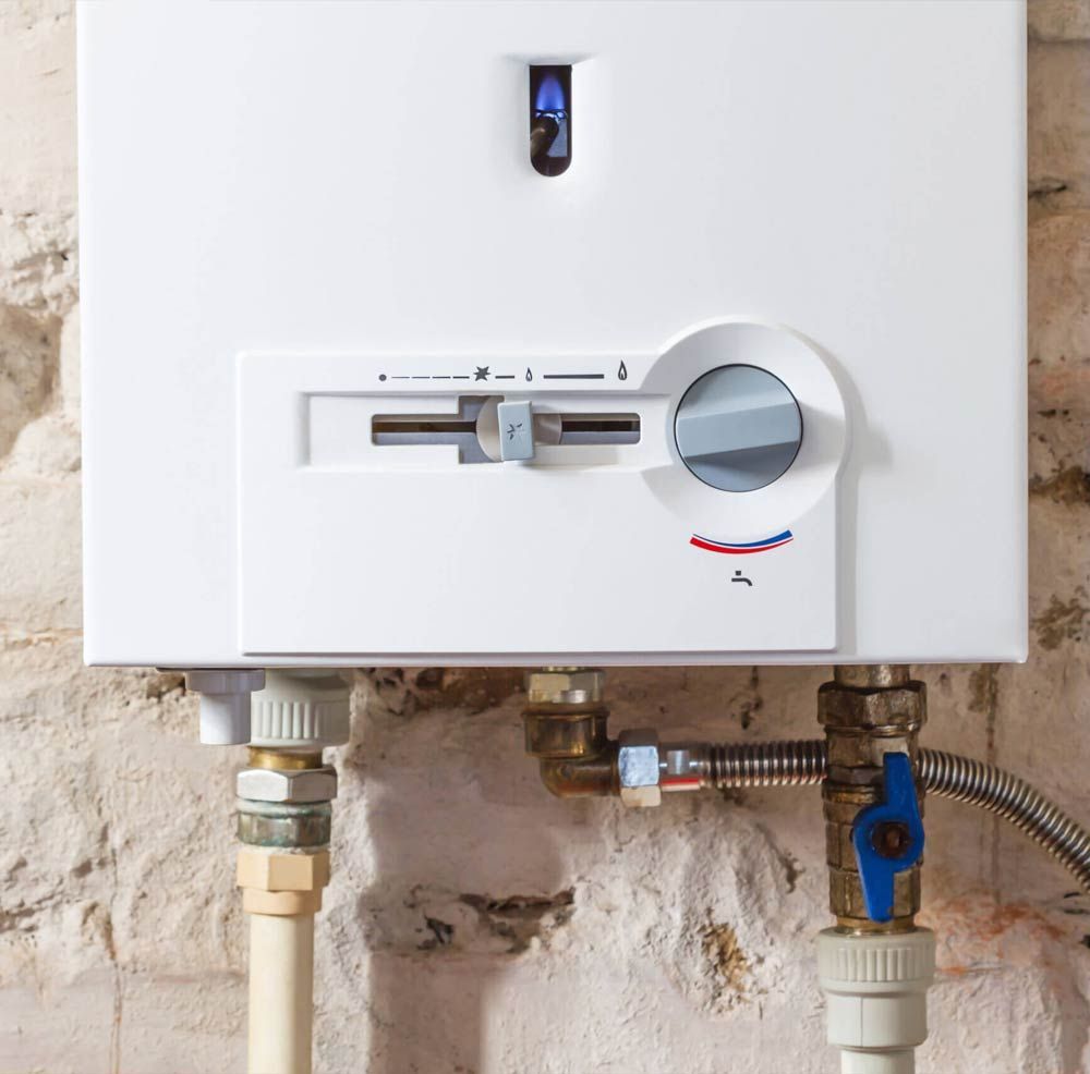 White wall-mounted gas water heater with pipes, valves, and a blue indicator light