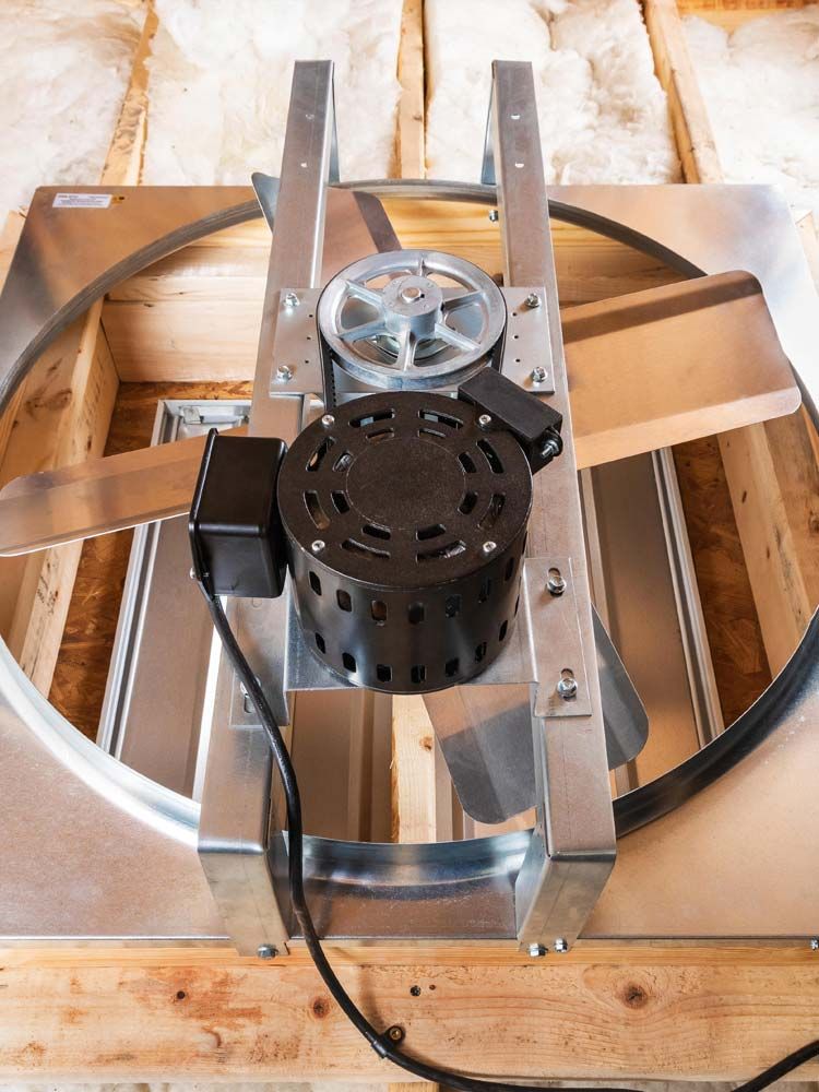 Mechanical device mounted on a wooden pallet, with a circular metal frame and central motor assembly.