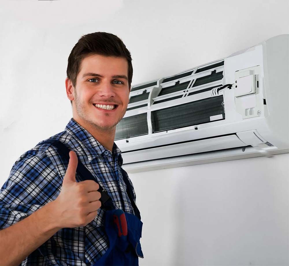 Technician smiling and giving thumbs up beside a wall-mounted air conditioner
