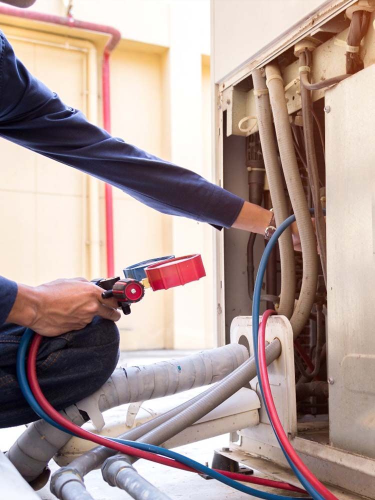 Technician using red spray nozzle to clean hoses and pipes inside an electrical or utility cabinet