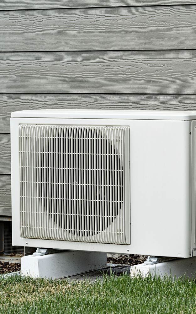 Outdoor air conditioning unit beside gray house siding, sitting on a concrete pad.
