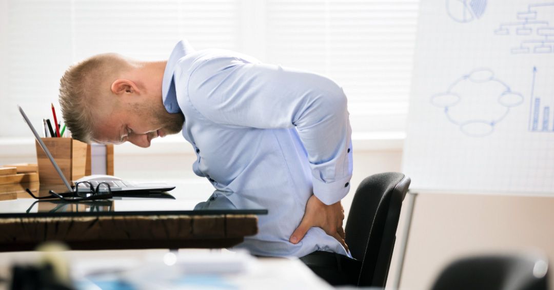 Office worker struggling with back pain from sitting all day.