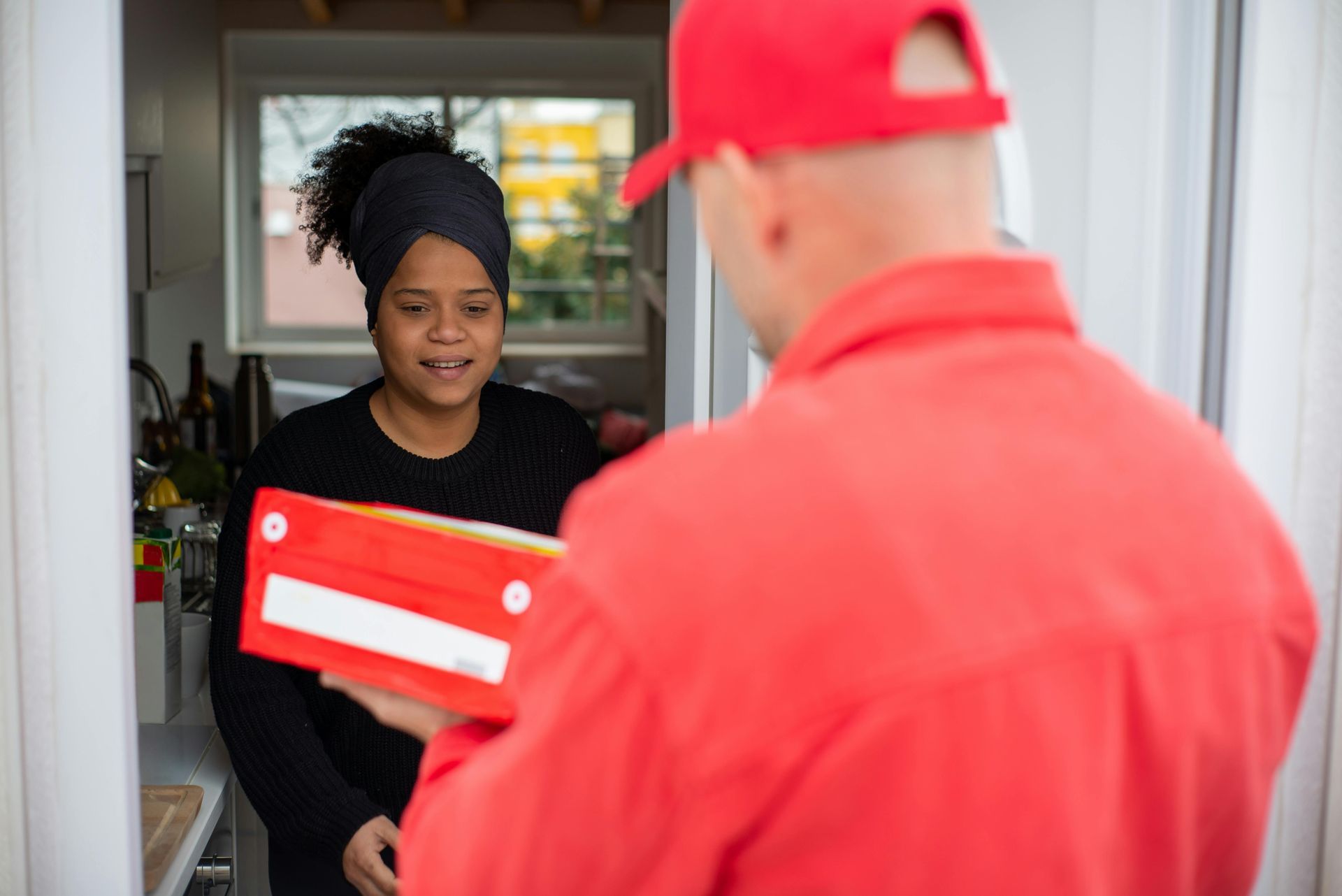 Person receiving a red box from a delivery person in a red uniform.