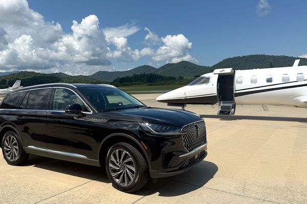 Black SUV parked next to a private jet on Signature Aviation Asheville tarmac with Blue Ridge mountains in the background.