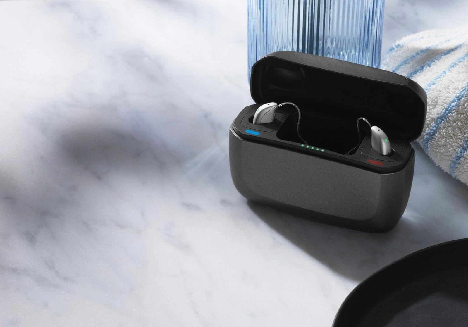 Auricolari aperti in una custodia di ricarica accanto a una seconda custodia di auricolari aperta su un tavolo di legno.