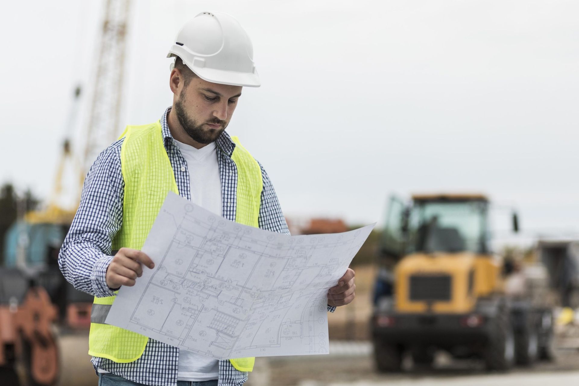 Operário da construção civil, usando capacete e colete de segurança.