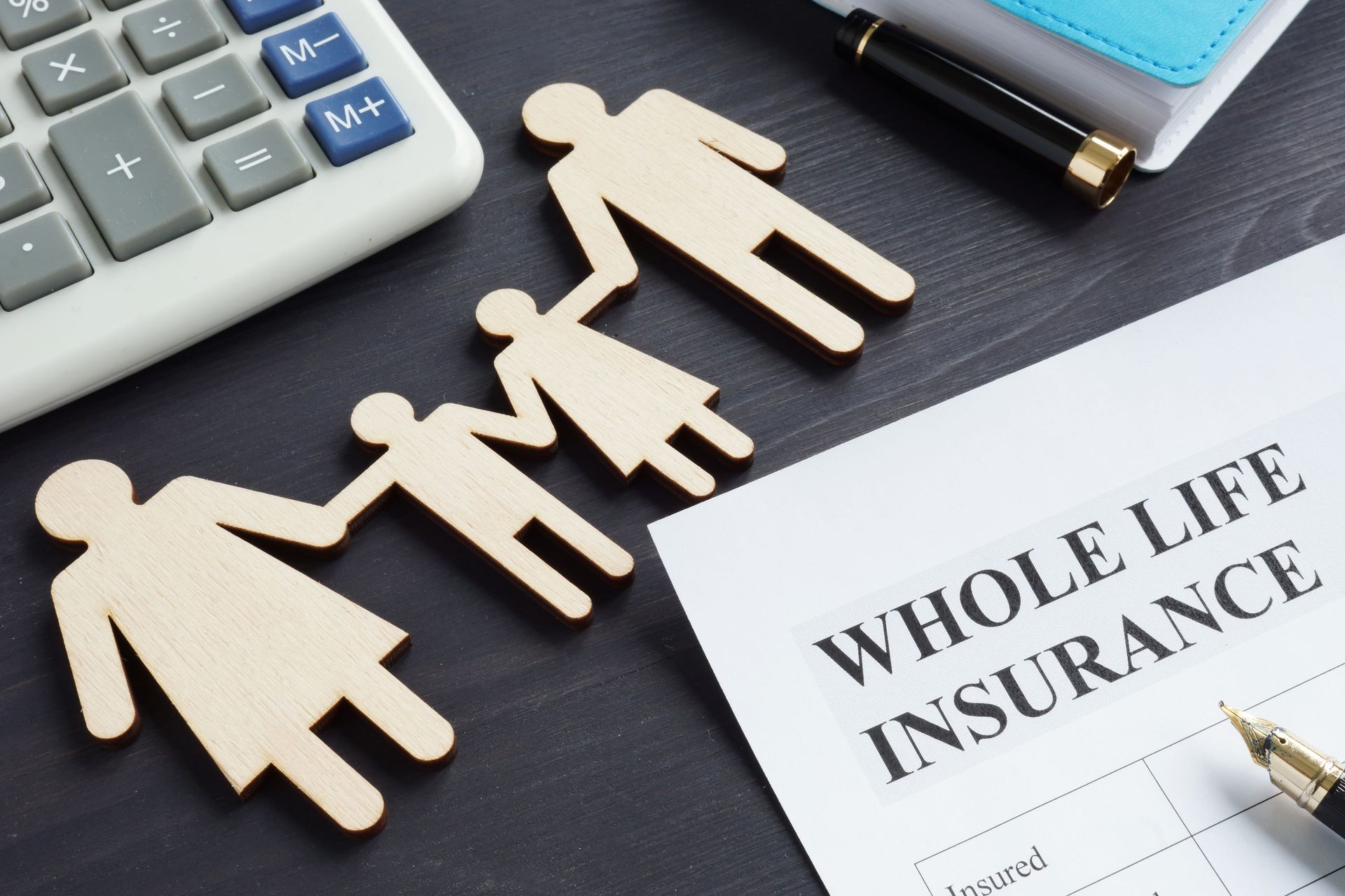 Wooden family figures beside a whole life insurance document on a desk, with a calculator and pen